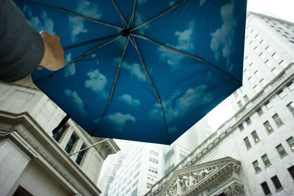 Blue umbrella with clouds near big houses