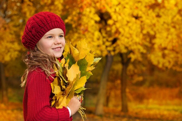 Ragazza nella foresta di autunno con una manciata di foglie gialle