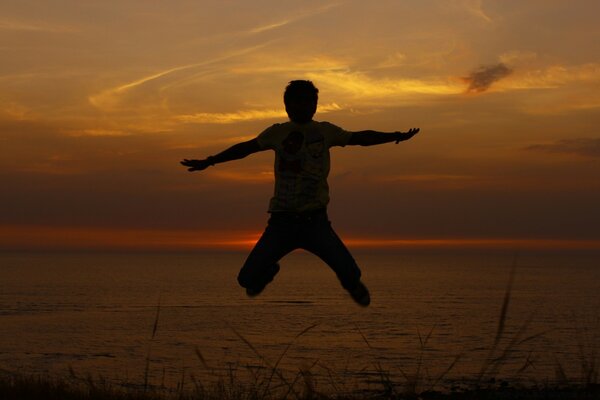 Photo of a jump on the background of a sunset on the sea