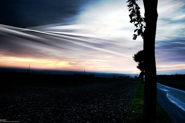 Die Straße, die im Hintergrund des Sonnenuntergangs in die Ferne führt