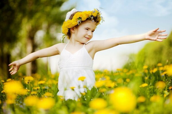 A girl in a wreath of dandelions on the field