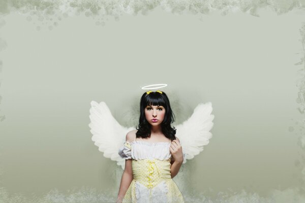 A girl in an angel costume on a neutral gray background