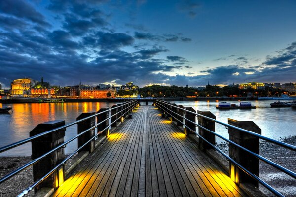 Puente al muelle por la noche iluminado por linternas