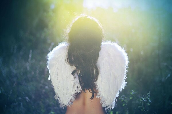 A girl with angel wings is standing with her back