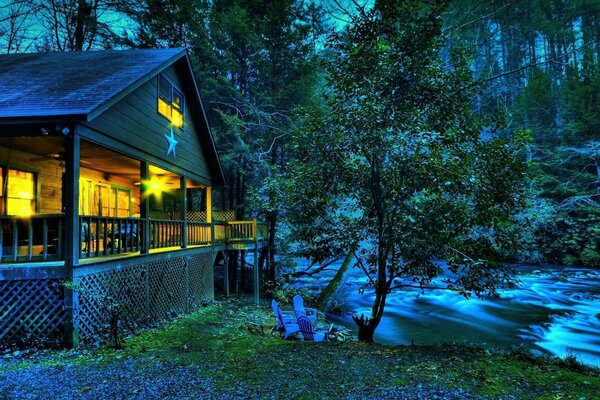 Casa nella foresta notturna vicino al fiume