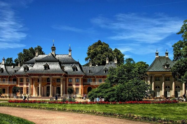 Bâtiment antique avec colonnes ciel bleu arbres verts route marche personnes