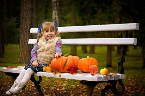 A girl on a bench with pumpkins