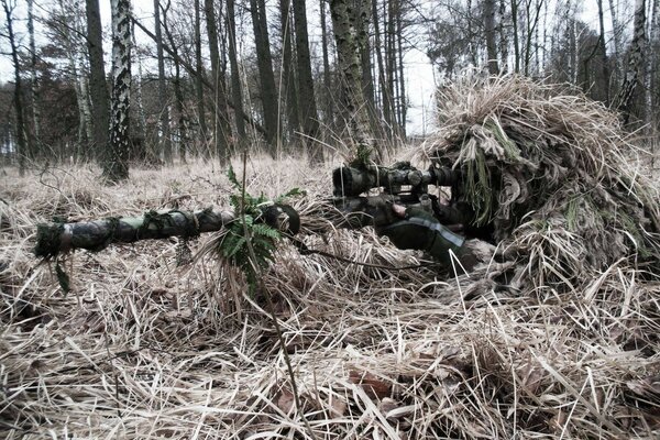 A hidden sniper with a rifle in the woods