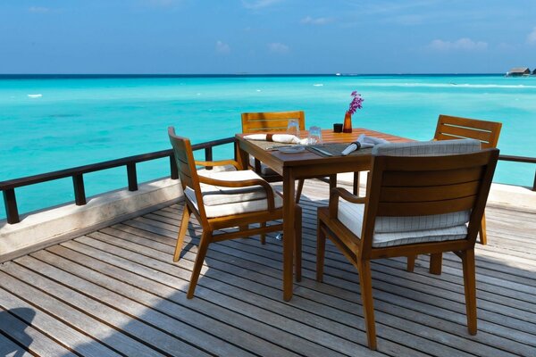 Vernada com mesa de jantar à beira-mar azul