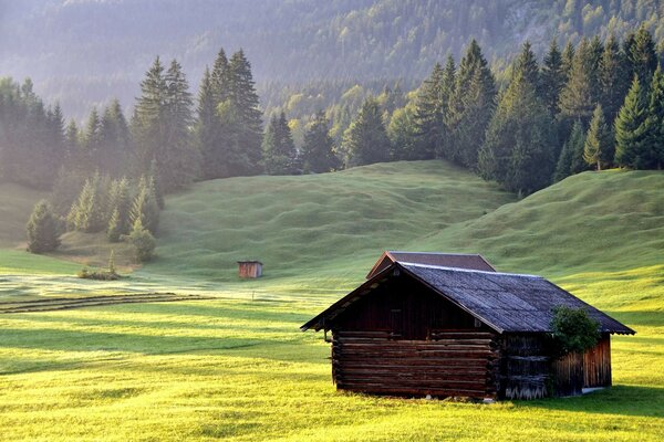 Um velho celeiro no fundo de uma paisagem de montanha