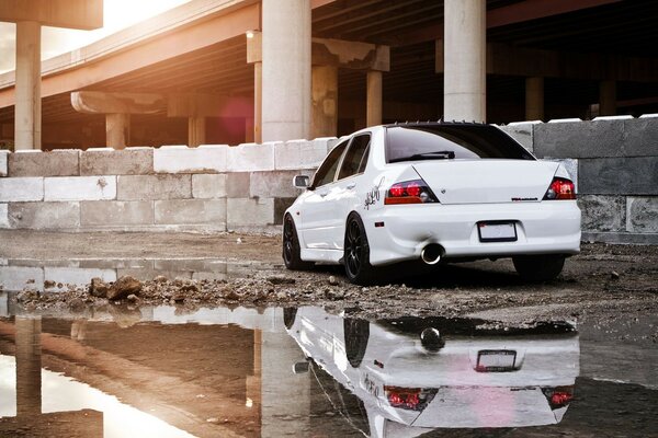 A white car is parked under the bridge