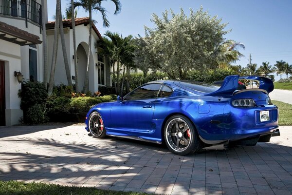 A sporty blue car is parked near the house