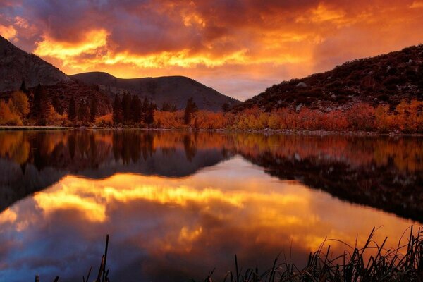 Reflexão do pôr do sol de fogo na água