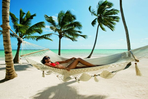 Chica descansando en una hamaca en la playa