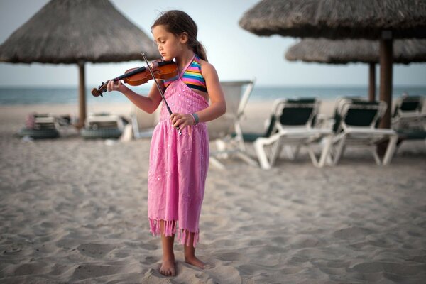 A girl with a violin on the beach