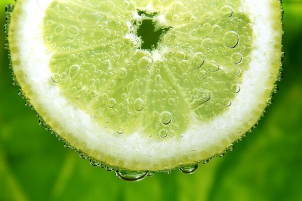 Lemon on a green background with water drops