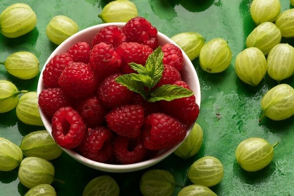 Gooseberries and raspberries on a green table