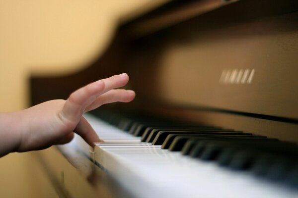 A small hand presses the piano keys