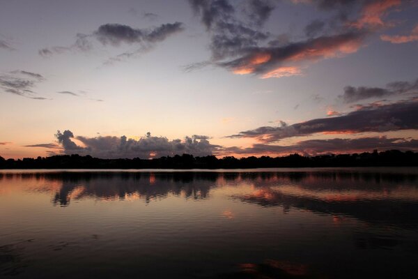 Późny Zachód słońca na tle leśnego jeziora
