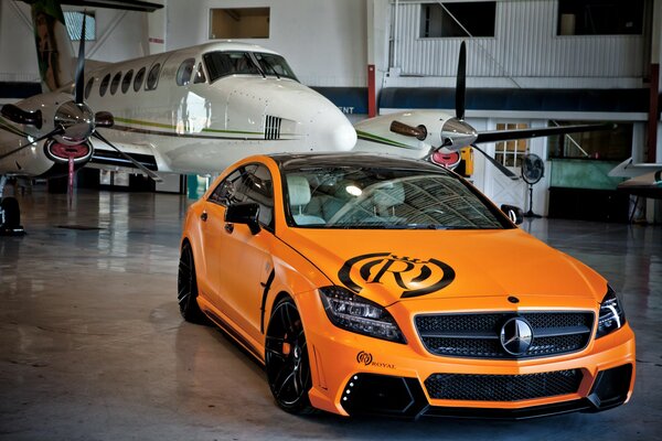 Orange sports car on the background of an airplane