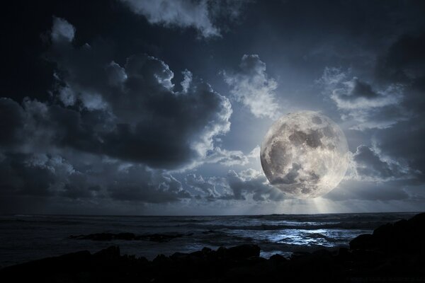 Una enorme Luna cuelga sobre el mar oscuro