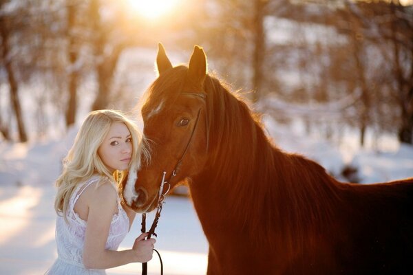 A girl with a horse. In the winter forest