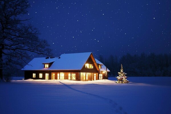 Casa à noite na neve com uma árvore de Natal