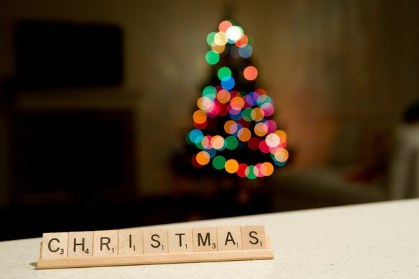 Letras de Navidad y árbol de Navidad borroso con guirnalda