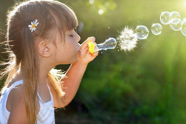 Fille avec de la camomille dans les cheveux laisse des bulles de savon