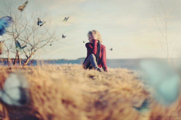 A girl is sitting with her hand near her hair