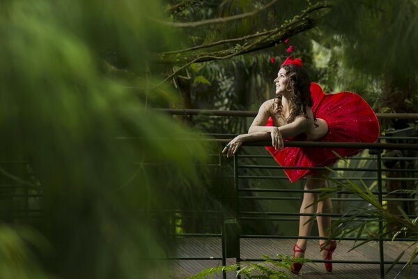 Una chica con un interesante vestido rojo está feliz de caminar en la selva tropical