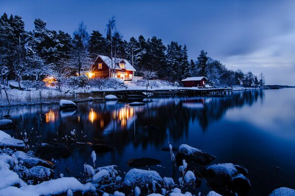 Bosque de invierno y casa en la orilla