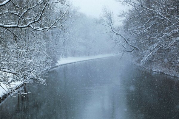 Icy river in snow-covered banks with trees