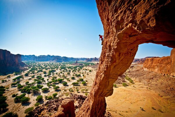 Ein Wüstenschlucht. Ein Athlet auf einer Klippe steigt nach oben