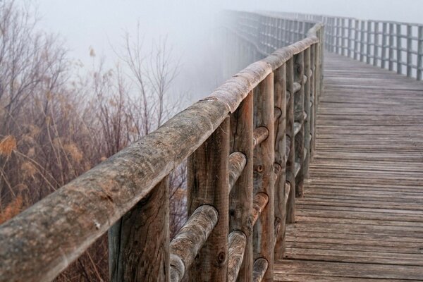 Eine Brücke aus Holz, die in den Nebel fällt