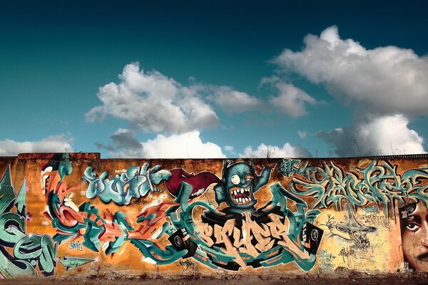 The wall is covered with graffiti under a blue sky