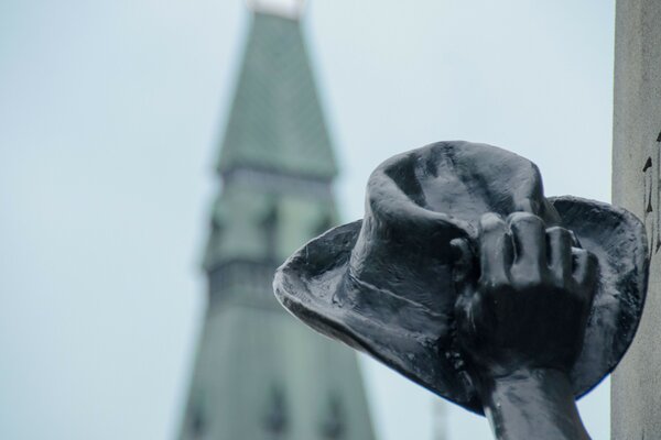 A hand holds a hat against the background of the roof