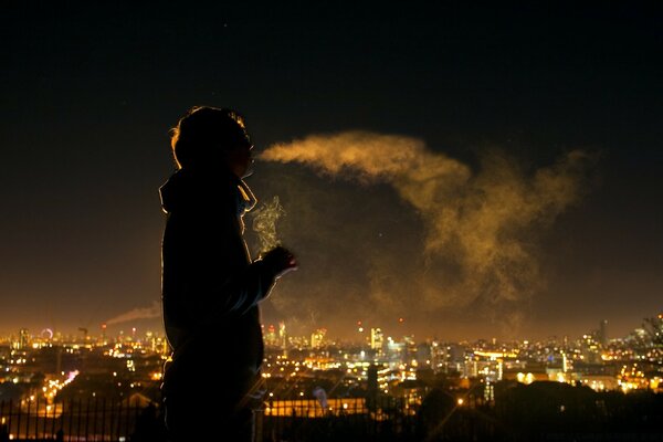 Homme fume sur fond de ville de soirée