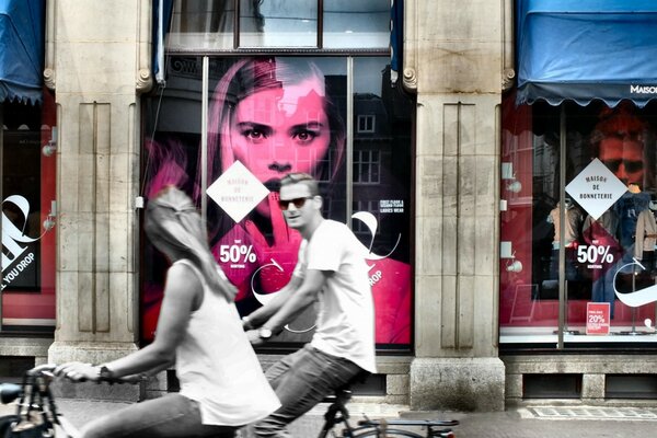 Two on bicycles on the background of a showcase