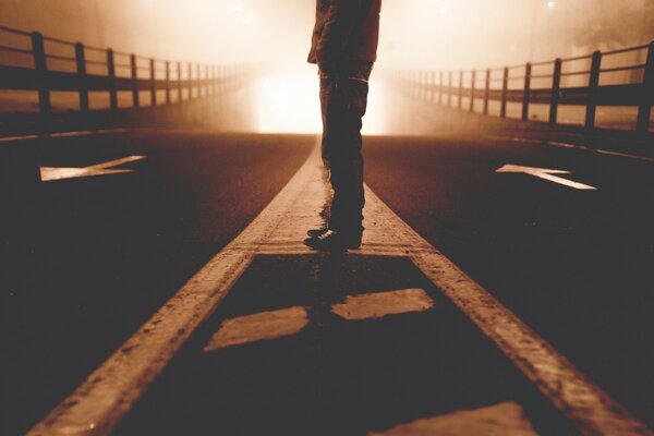 Un homme qui ne voit pas son visage se tient sur un pont