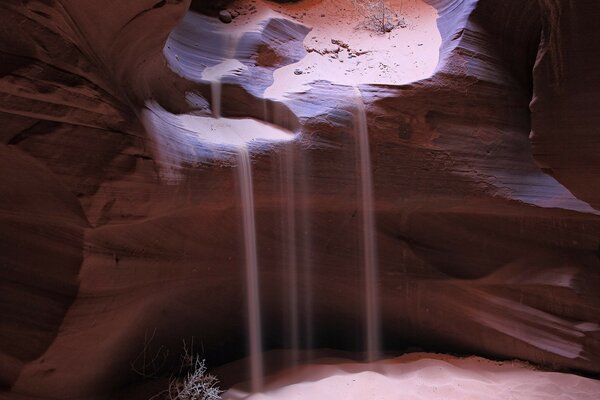 Sand wird in eine Höhle im Felsen gegossen