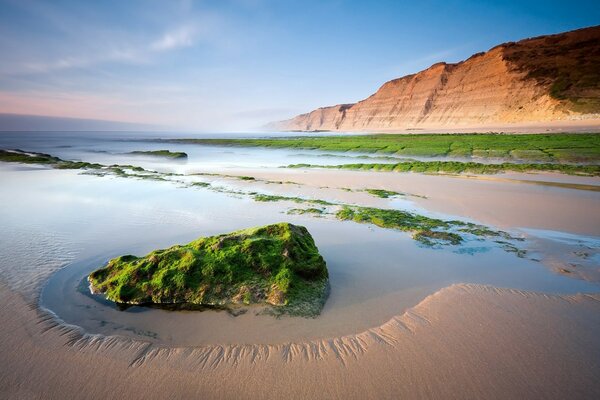 Pedregulhos e pedras na areia contra o fundo das rochas