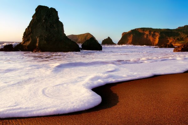 Foamy waves roll onto a sandy beach