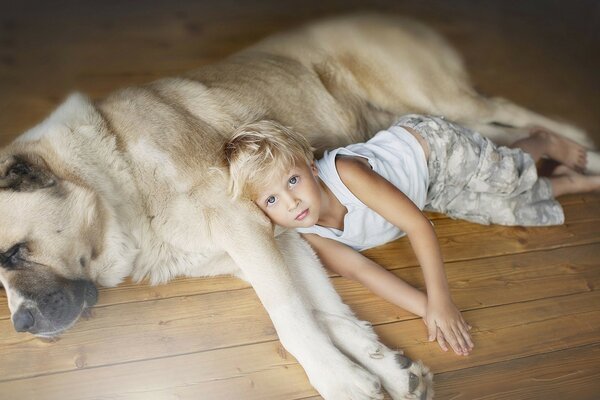 The boy is lying next to his beloved dog