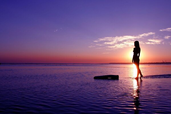 Bela foto de uma menina ao pôr do sol na água