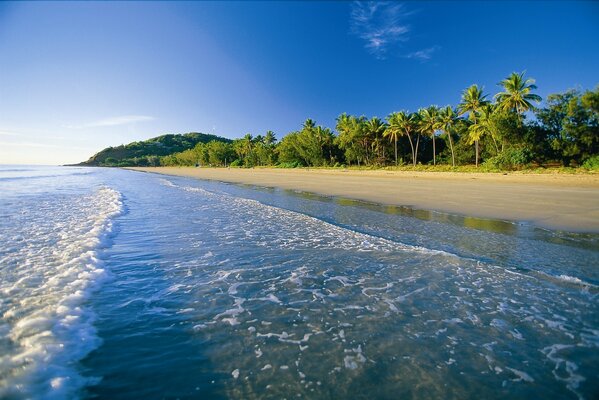 Foamy waves roll onto the shore of a tropical island