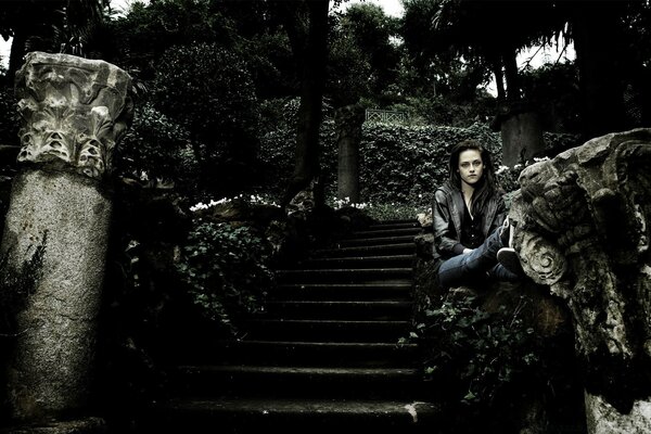 The actress is sitting on an old gloomy staircase