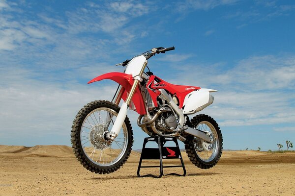 Классный красный с белым гоночный мотоцикл на фоне пустынной местности