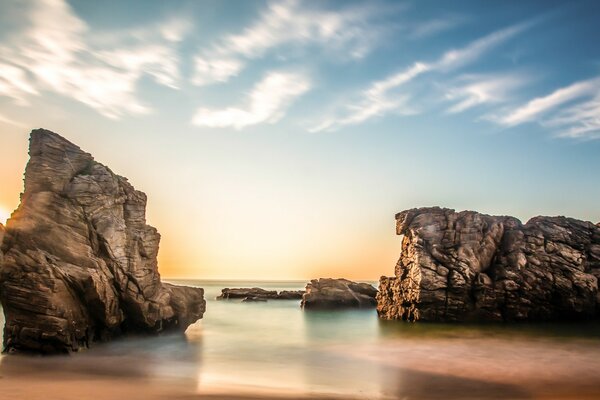 Amanecer sobre aguas tranquilas con rocas