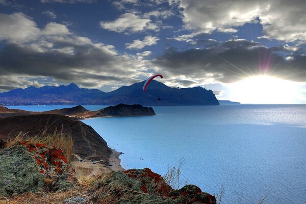 Paracadutista in parapendio che sorvola il lago